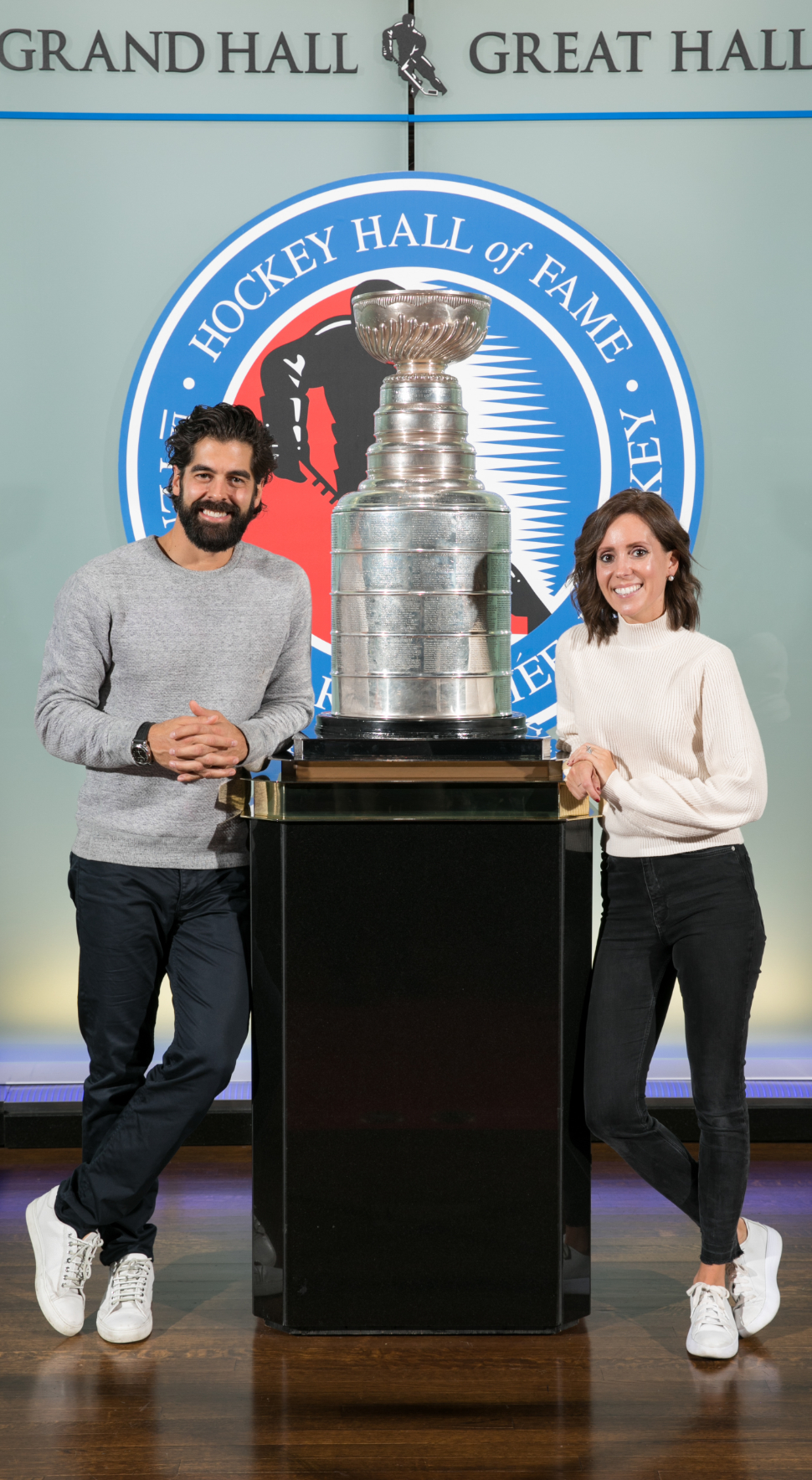 Couple stand on either side of the Stanley Cup in the Great Hall at the Hockey Hall of Fame